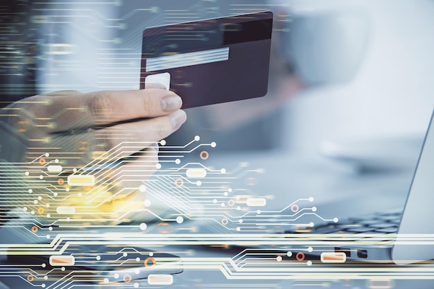 Doble exposición de una mujer que compra en línea con una tarjeta de crédito y un holograma de tema de datos que dibuja el concepto de comercio electrónico