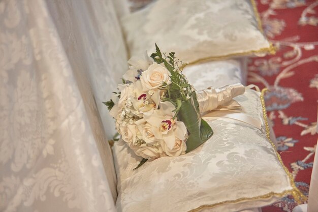 El doble ramo que descansa sobre los cojines blancos del banco de bodas en el interior de la iglesia.