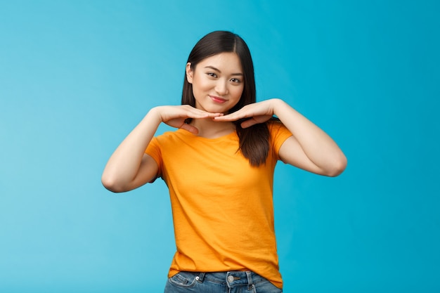 Doce adorável tenra menina asiática morena inclinar a cabeça sorrindo mostrar rosto limpo e puro segurar as palmas das mãos sob o queixo ...