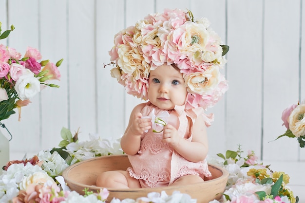 Doce bebê engraçado no chapéu com flores. páscoa. menina bonito 6 meses usando chapéu de flor.
