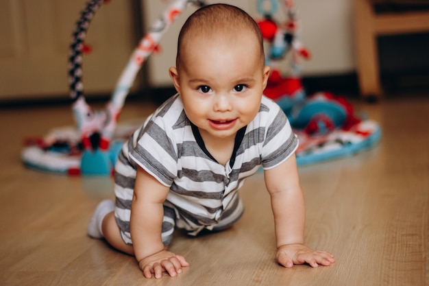 Doce bebezinho aprendendo a engatinhar em casa. criança sorridente com bochechas rechonchudas