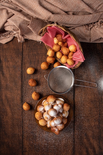 Doce brasileiro chamado bolinho de Chuva, coberto de açúcar, sobre madeira rústica, vista de cima.