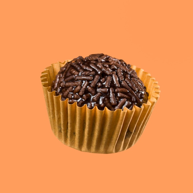 Doce brasileiro vegano chamado bolas de chocolate Brigadeiro isoladas em fundo laranja