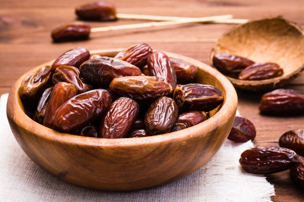 Doce datas secas de frutas em uma tigela de madeira em cima da mesa