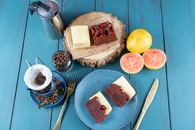 Foto doce de goiaba com queijo cercado por xícara e grãos de café em uma vista de mesa azul