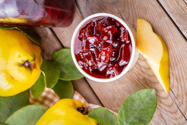 Doce de marmelo caseiro em uma jarra de vidro em um fundo de madeira velho. Frutas e folhas frescas de marmelo e geleia de marmelo. (nome turco; ayva receli)