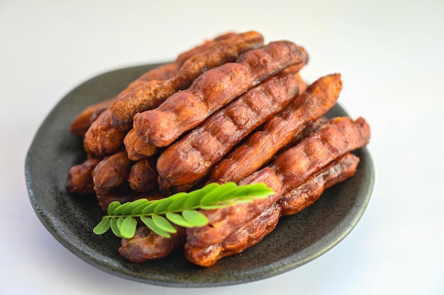 Doce de tamarindo para comida frutas tamarindos maduros no prato e fundo branco Casca de tamarindo frutas tropicais verão