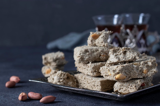 Doce girassol halva com amendoim na bandeja de metal em fundo cinza escuro