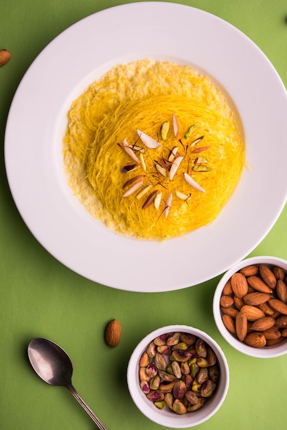 Doce indiano kesar sutarfeni ou sutar feni ou firni ou seviyan ou laccha, farinha de arroz fragmentada torrada em ghee, misturada com açúcar derretido para formar um algodão doce, com pistache e amêndoas