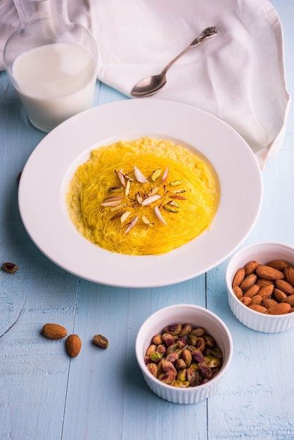 Doce indiano kesar sutarfeni ou sutar feni ou firni ou seviyan ou laccha, farinha de arroz fragmentada torrada em ghee, misturada com açúcar derretido para formar um algodão doce, com pistache e amêndoas