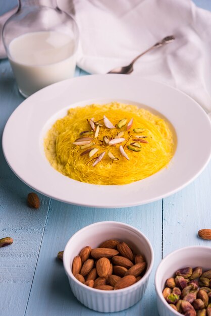 Doce indiano kesar sutarfeni ou sutar feni ou firni ou seviyan ou laccha, farinha de arroz fragmentada torrada em ghee, misturada com açúcar derretido para formar um algodão doce, com pistache e amêndoas