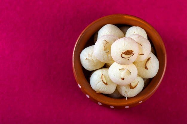 Doce indiano ou sobremesa - Rasgulla, doce bengali famoso na tigela de barro no rosa.