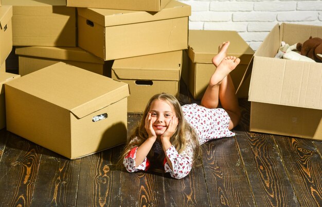 Doce lar Menina relaxando depois de desembalar as caixas Conceito de mudança Sentindo-se bem em casa Sonhando com móveis para casa Mudando-se para casa Alugar Serviço de entrega Apartamento para família