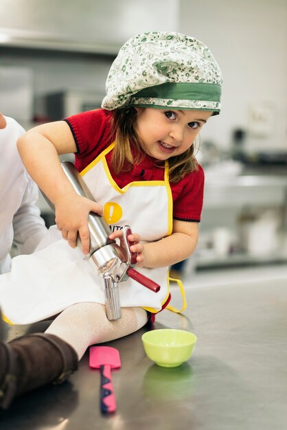 Doce menina feliz cozinhando em uma cozinha.