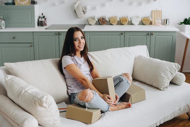 Doce menina senta-se no sofá com caixas Freelancer Girl trabalhando em casa Cozy Couch Kitchen