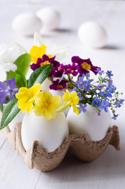 Foto una docena de huevos en una bandeja con flores sobre la mesa.