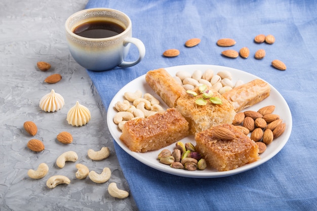 Doces árabes tradicionais (basbus, kunafa, baklava), uma xícara de café e nozes vista lateral, close-up.