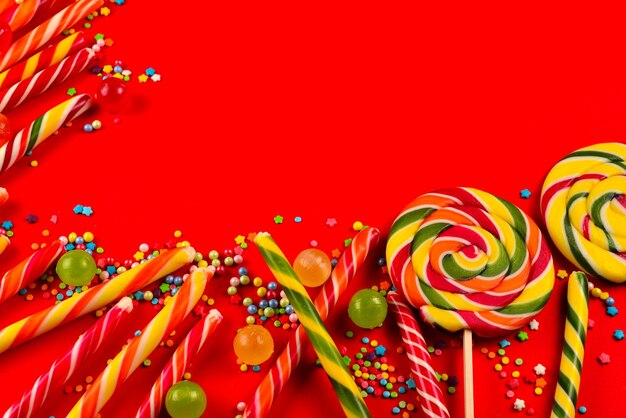 Doces coloridos em um fundo vermelho lollipop vista superior copiar espaço