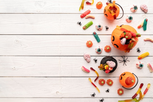 Foto doces coloridos para festa de halloween em fundo branco de madeira, vista superior