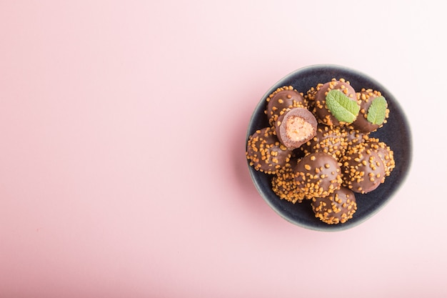 Doces de bola de caramelo de chocolate com amêndoas em um fundo rosa pastel. vista superior, copie o espaço.