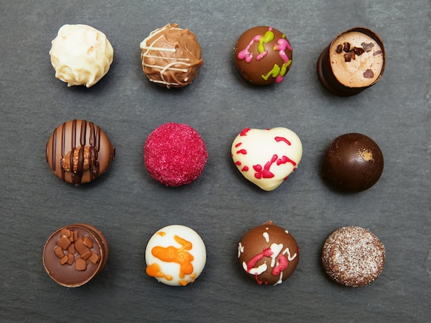 Foto doces de bombons de chocolate coloridos em um fundo de bandeja de ardósia cinza