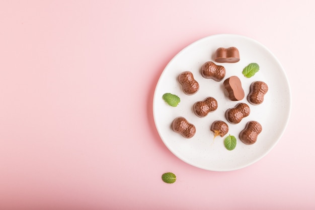 Doces de chocolate caramelo em um fundo rosa pastel. vista superior, copie o espaço