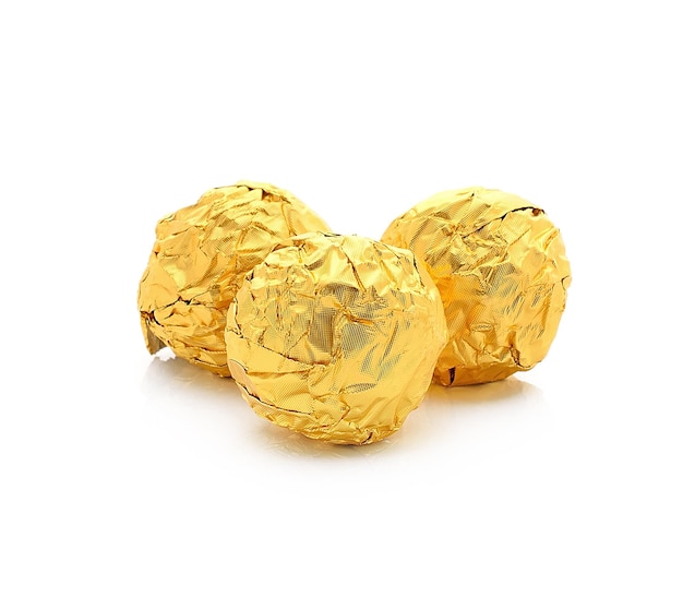 Foto doces de chocolate doce embrulhados em folha de ouro isolado no fundo branco