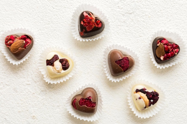 doces de chocolate em forma de coração com frutas e nozes em um fundo colorido vista superior com espaço para texto conceito de feriado