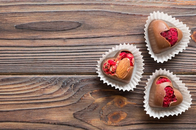 doces de chocolate em forma de coração com frutas e nozes em um fundo colorido vista superior com espaço para texto conceito de feriado