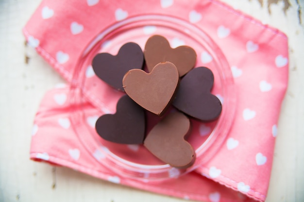Doces de chocolate em forma de coração em um prato com toalha rosa