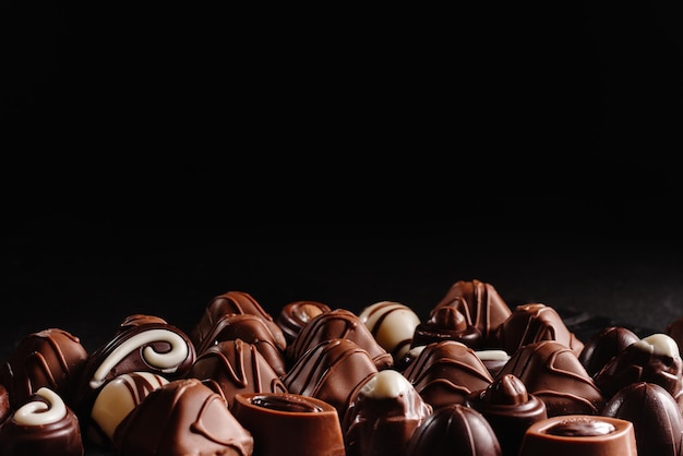 Doces de chocolate em uma vista superior de fundo escuro muitos chocolates diferentes uma variedade de deliciosos
