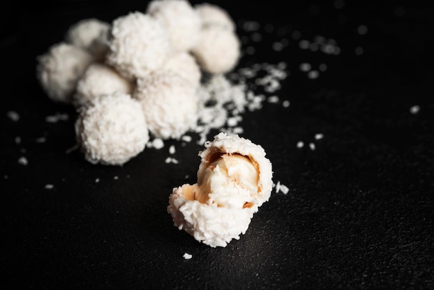 Doces de coco com nozes em fundo escuro raffaello em fundo preto foto de alta qualidade