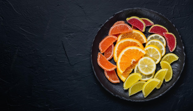 Doces de geleia de marmelada multicolorida e pedaços de laranja e limão