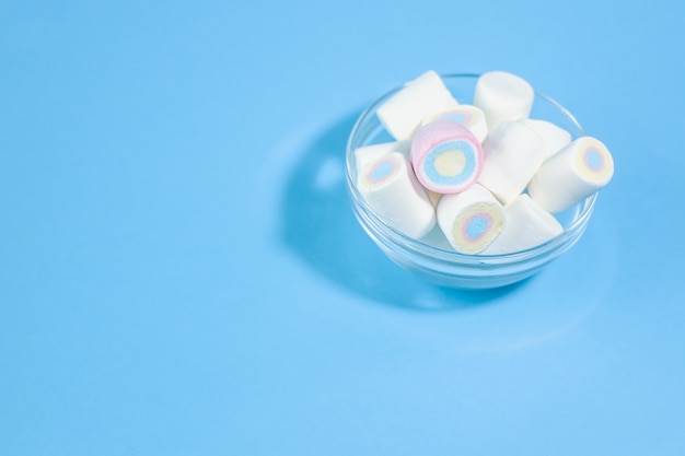 Doces de mini marshmallow em fundo azul claro com espaço livre para título