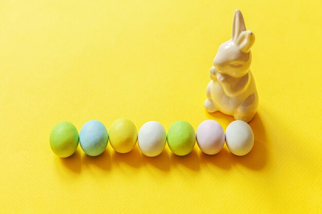Doces de Páscoa, ovos de chocolate, doces e coelho de brinquedo isolado em um fundo amarelo na moda