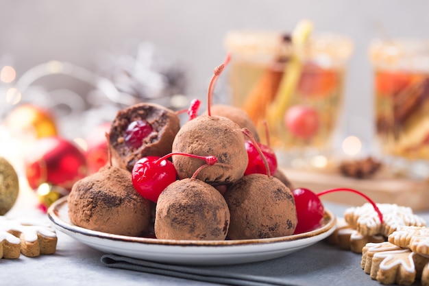 Doces doces de Natal em cima da mesa de sobremesa. Bolas de biscoito com cereja - loli pop ou bolo pop. Decoração de ano novo e bebida de cidra de maçã. conceito feliz holidey