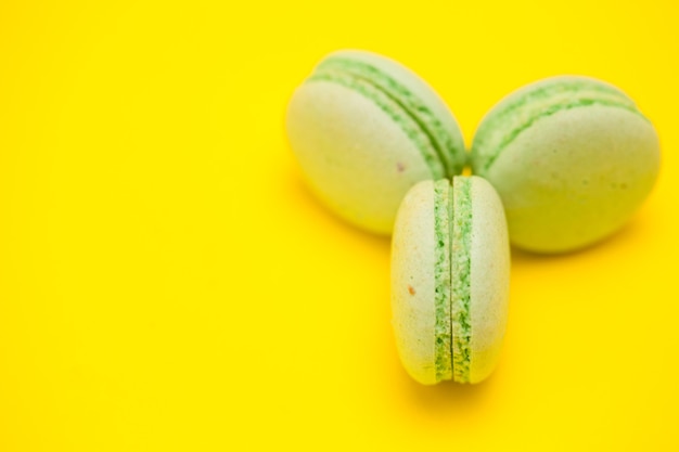 Doces e deliciosos macaroons verdes sobre fundo amarelo.