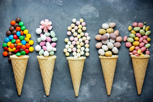 Doces em cones de waffle em fundo escuro