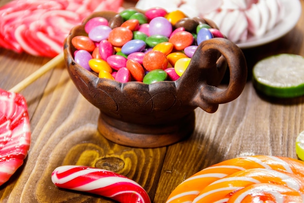 Doces em forma de botão colorido cheios de chocolate em tigela de cerâmica na mesa de madeira