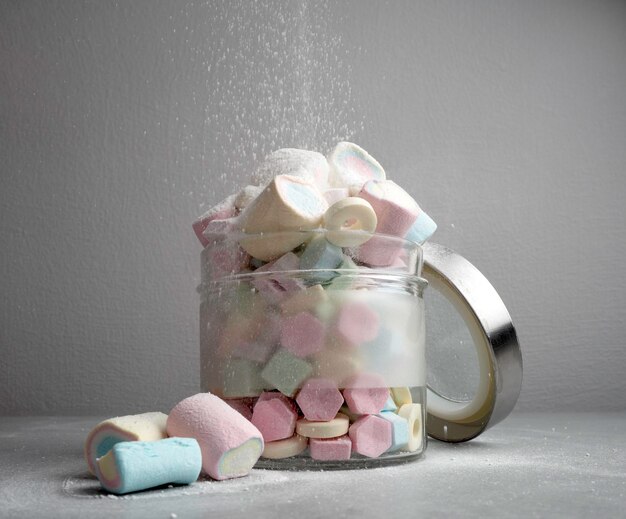 Doces multicoloridos e marshmallow nas mãos das crianças e em pote de vidro