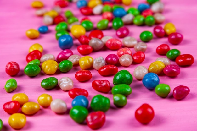 Doces multicoloridos em um fundo rosa de madeira.