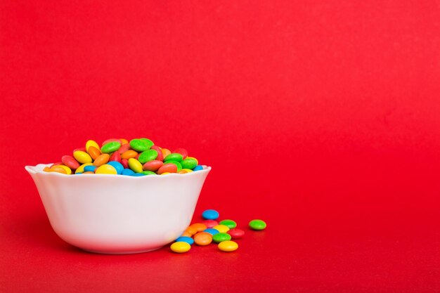 Doces multicoloridos em uma tigela em um fundo colorido conceito de aniversário e feriado Vista superior com espaço de cópia