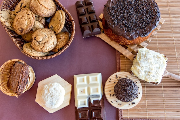 Doces na mesa. Bolo de chocolate, biscoitos, brownie e barra de chocolate. Vista do topo.