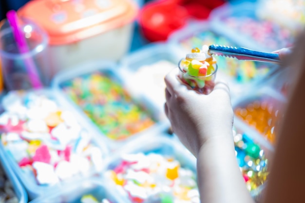 Foto doces são vendidos em caixinhas e cestinhas de balas de gelatina de várias cores compradores estão pegando copos