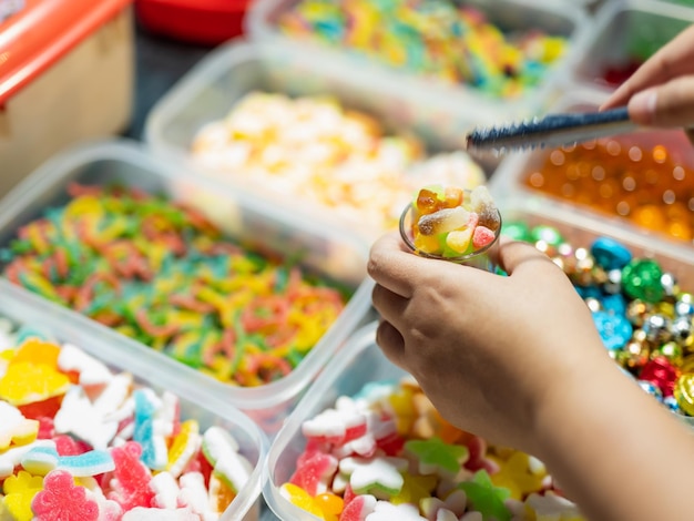 Foto doces são vendidos em caixinhas e cestinhas de balas de gelatina de várias cores compradores estão pegando copos