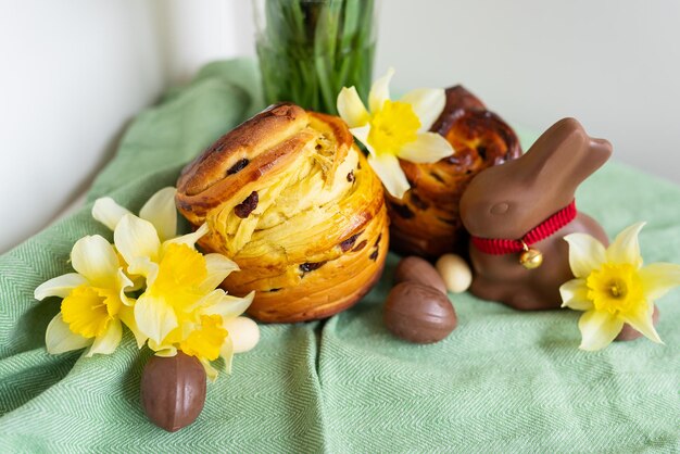 Doces tradicionais caseiros da Páscoa estão sobre um guardanapo verde junto com flores de narciso coelho ovos de chocolate Cozimento e decoração da Páscoa