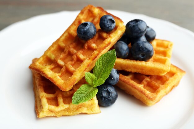 Doces waffles caseiros com bagas da floresta e calda de chocolate no fundo da mesa