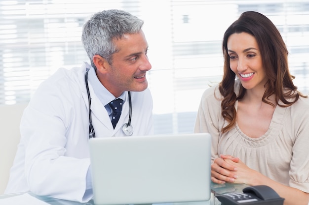 Docter mostrando algo en la computadora portátil a su paciente