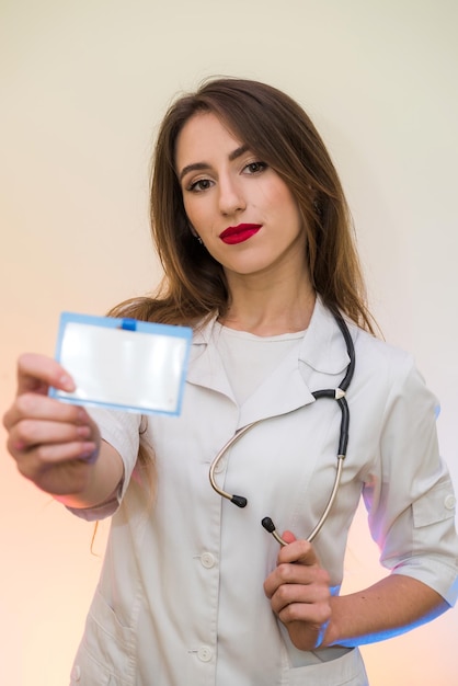 Doctor alegre y atractivo en uniforme médico posando con estetoscopio y placa en el hospital