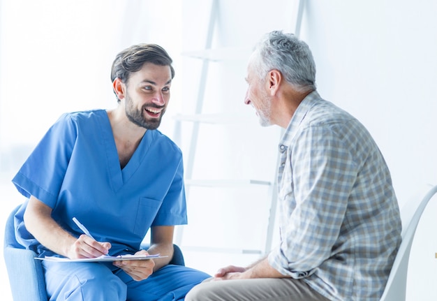 Doctor alegre hablando con paciente anciano